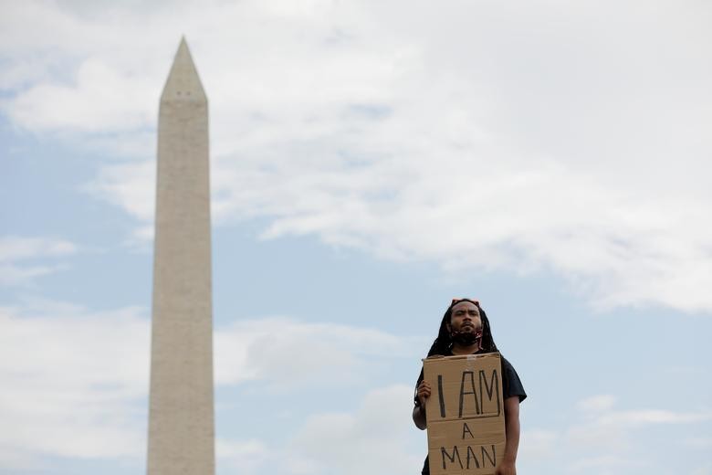 Aaron Xavier Wilson holds a sign during a "Get Your Knee Off Our Necks" march. REUTERS/Andrew Kelly